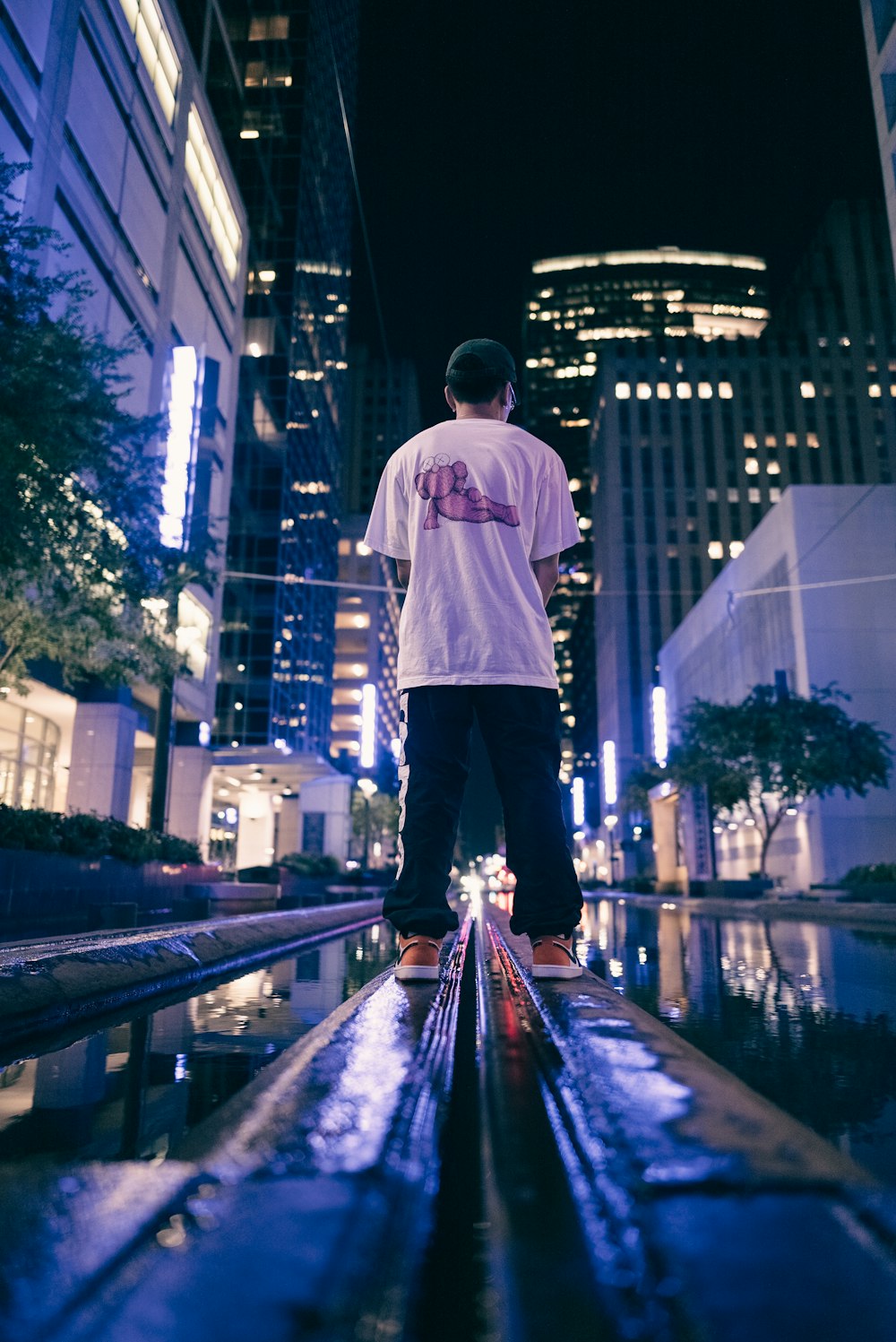 a skateboarder is standing in the middle of a city at night