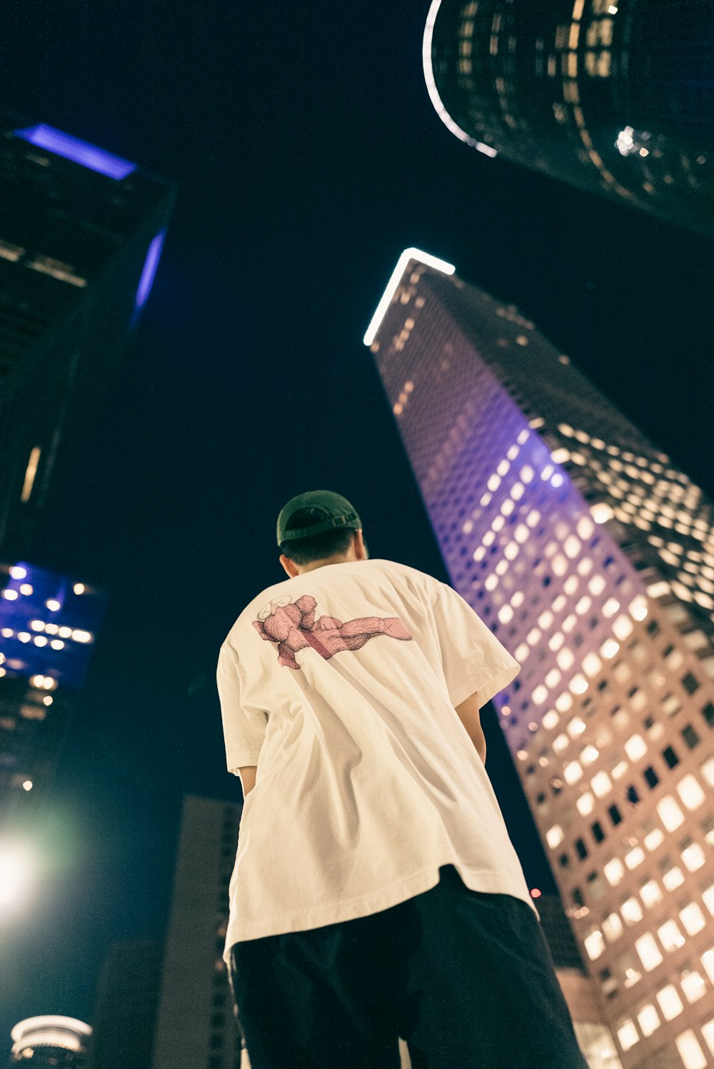 a man standing in front of tall buildings at night