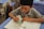 A focused student taking notes during an online English exam preparation class.