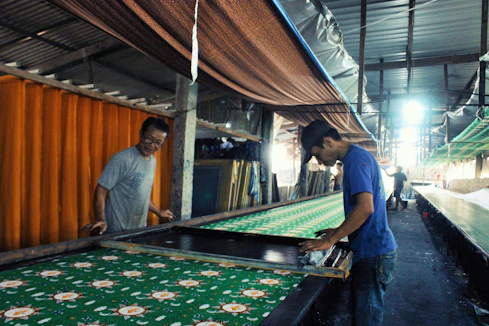 A lively workshop scene with participants printing designs on fabric under guidance.