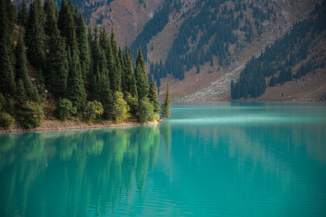 a body of water surrounded by mountains and trees, Instagram: @zvandrei