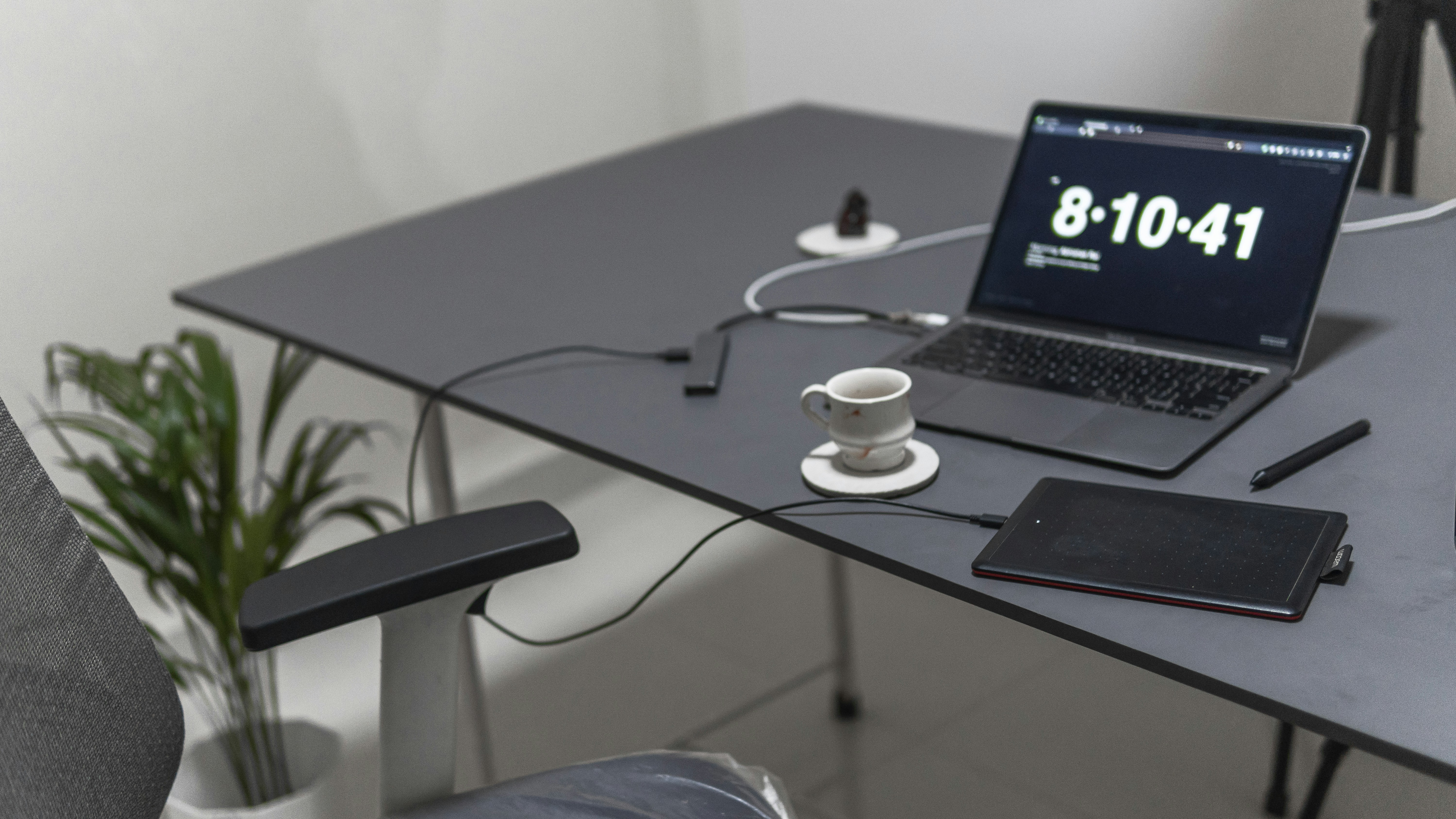 Minimalist workspace with a laptop, notebook, and coffee cup in black, gray, and white tones.