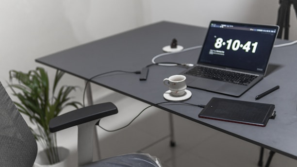 Minimalist office workspace with a laptop and a cup of coffee on a clean white desk.