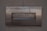 A metal mailbox with the word 'ENVELOPES' engraved on its front panel, set against a textured concrete wall. The surface shows signs of age with some rust marks.