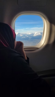 Smiling traveler looking out airplane window at clouds