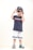 A young child stands confidently wearing a navy blue t-shirt with a red and white stripe, light gray shorts with blue stripes, and colorful Crocs. The child accessorizes with sunglasses and a cap worn backwards, striking a playful pose.