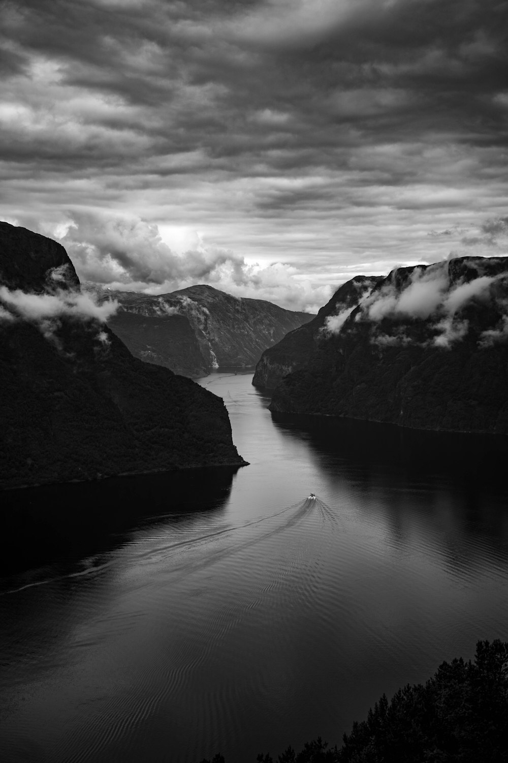a black and white photo of a body of water surrounded by mountains