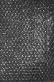 A textured surface of transparent bubble wrap with evenly distributed small air-filled bubbles.
