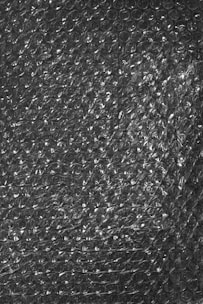A textured surface of transparent bubble wrap with evenly distributed small air-filled bubbles.