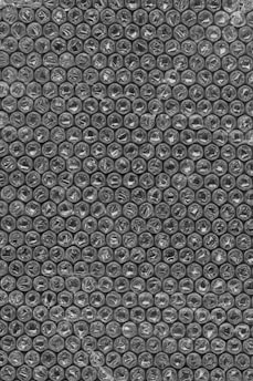 A close-up view of bubble wrap featuring a repetitive pattern of small, air-filled plastic bubbles arranged in neat rows and columns. The texture of the bubbles is semi-transparent and shiny.