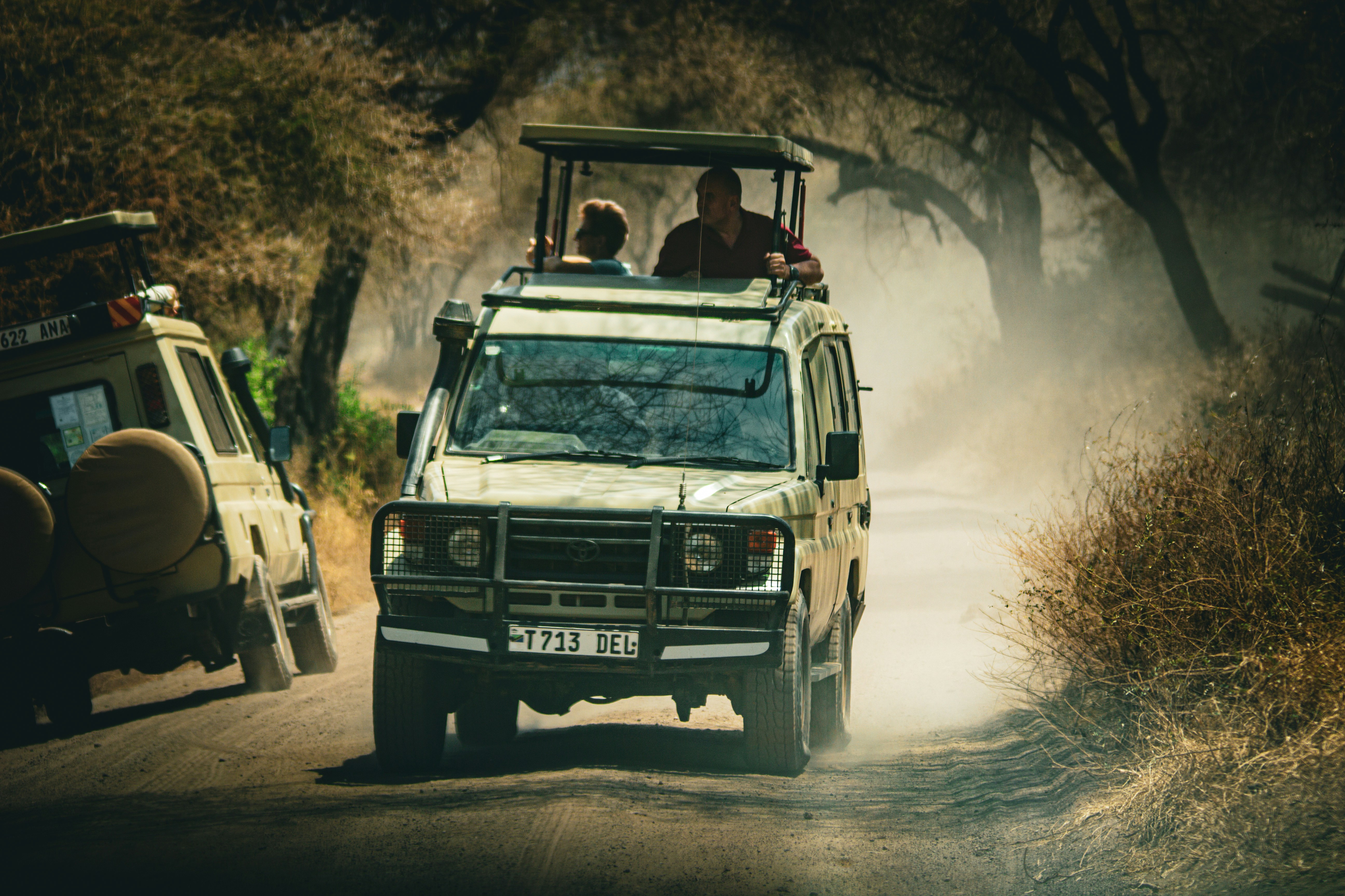 a safari vehicle driving down a dirt road, 