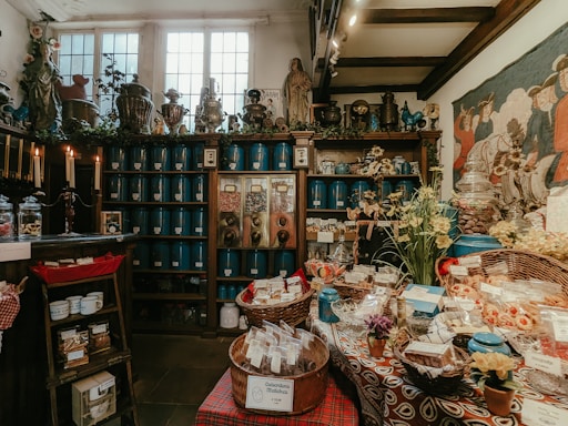 A warm, inviting photo of a small shop counter displaying jars of shea butter and colorful Ghanaian fabrics.