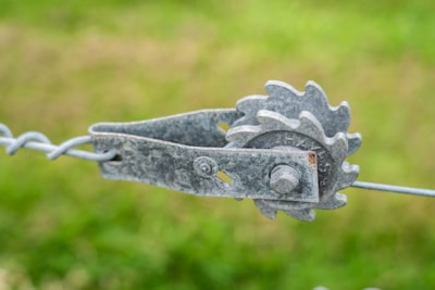Close-up of hands fixing a metal fence with tools.