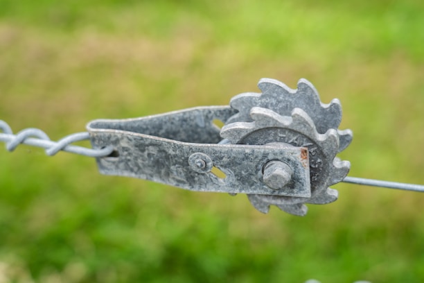 Close-up of a professional team member fixing a metal fence with tools.