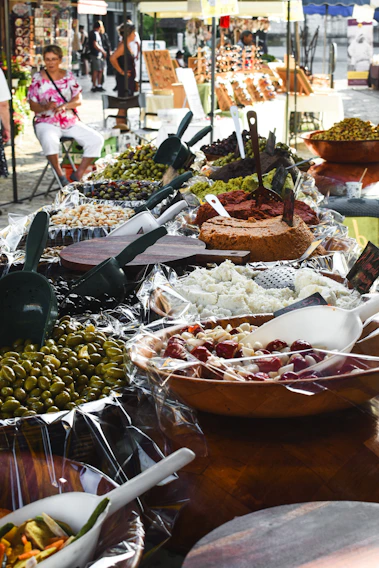 A vibrant market stall showcasing a variety of fresh Spanish olives and cured meats.