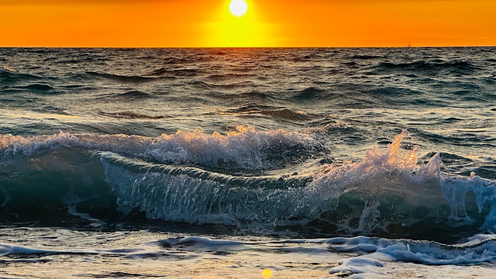 the sun is setting over the ocean waves