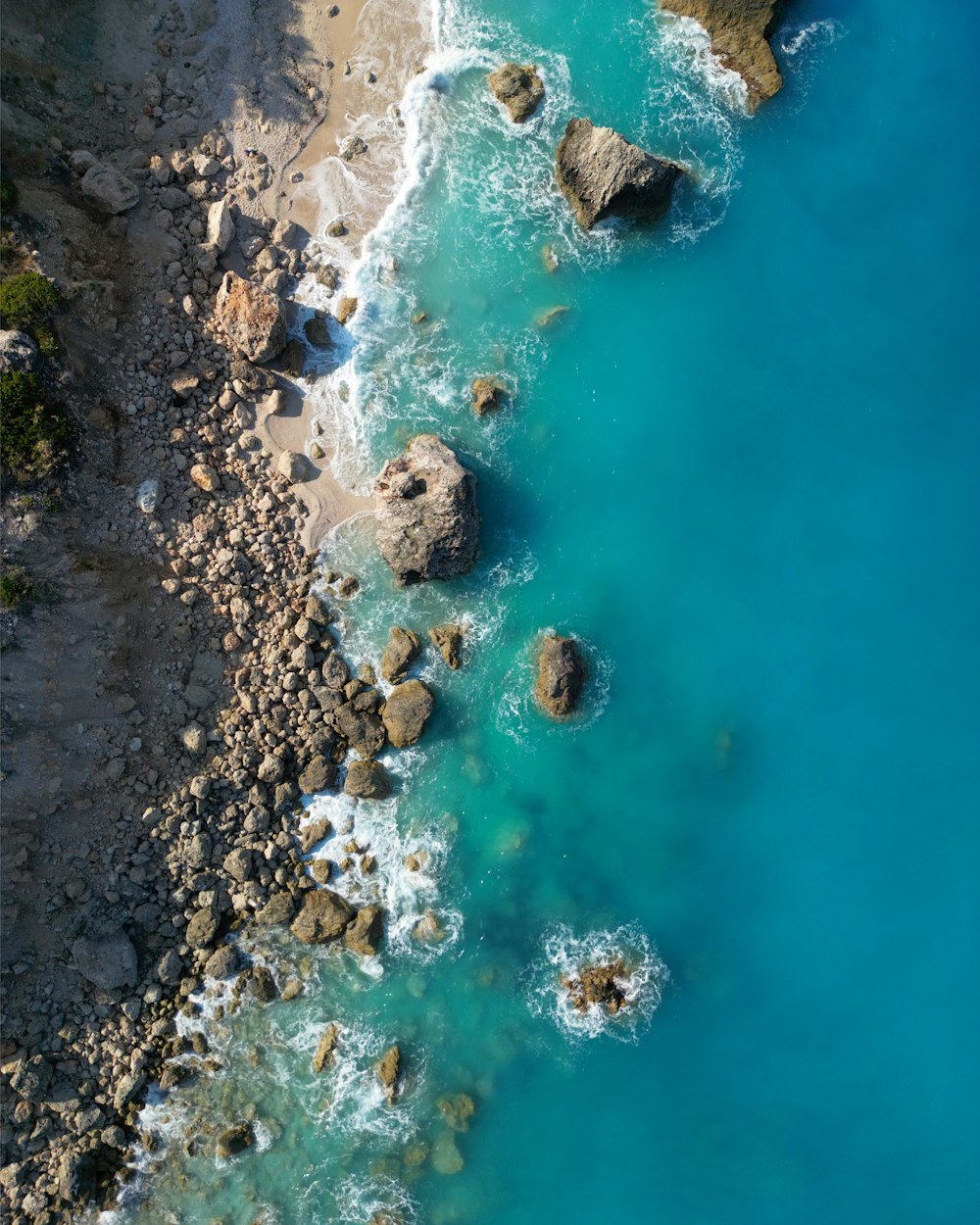 an aerial view of a beach with rocks and water