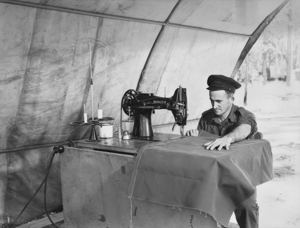 a man sitting at a table with a sewing machine