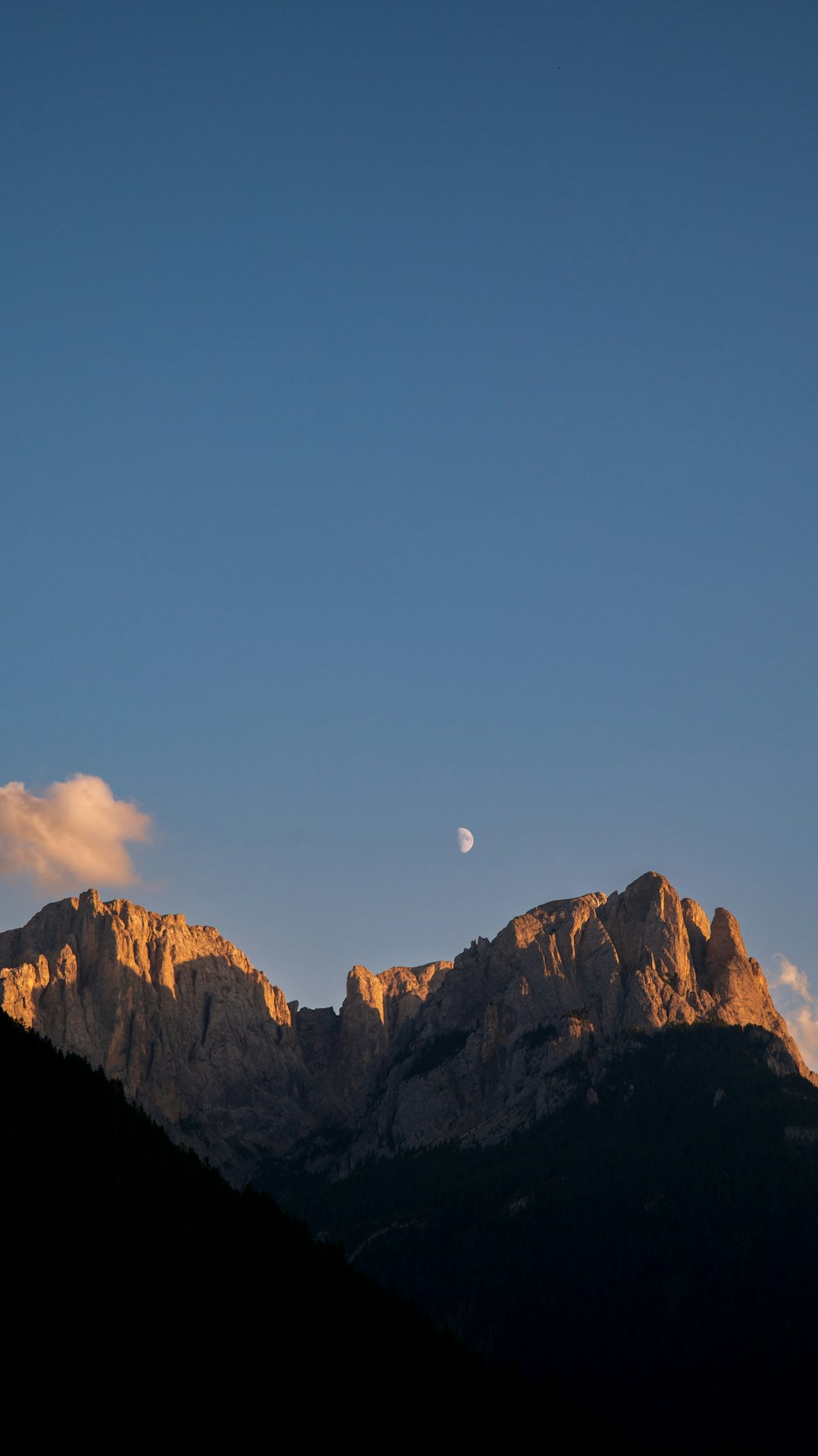 a view of a mountain with a half moon in the sky