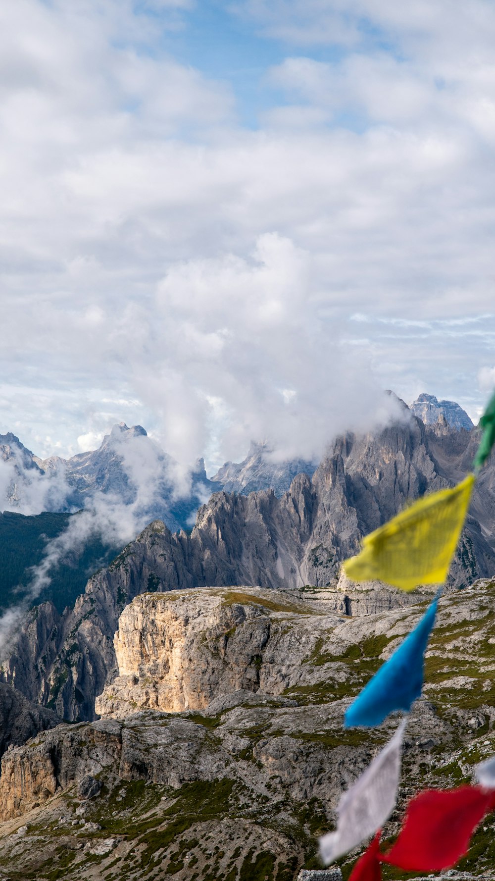 a group of flags flying in the wind on top of a mountain