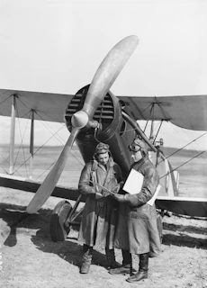a couple of men standing next to an airplane