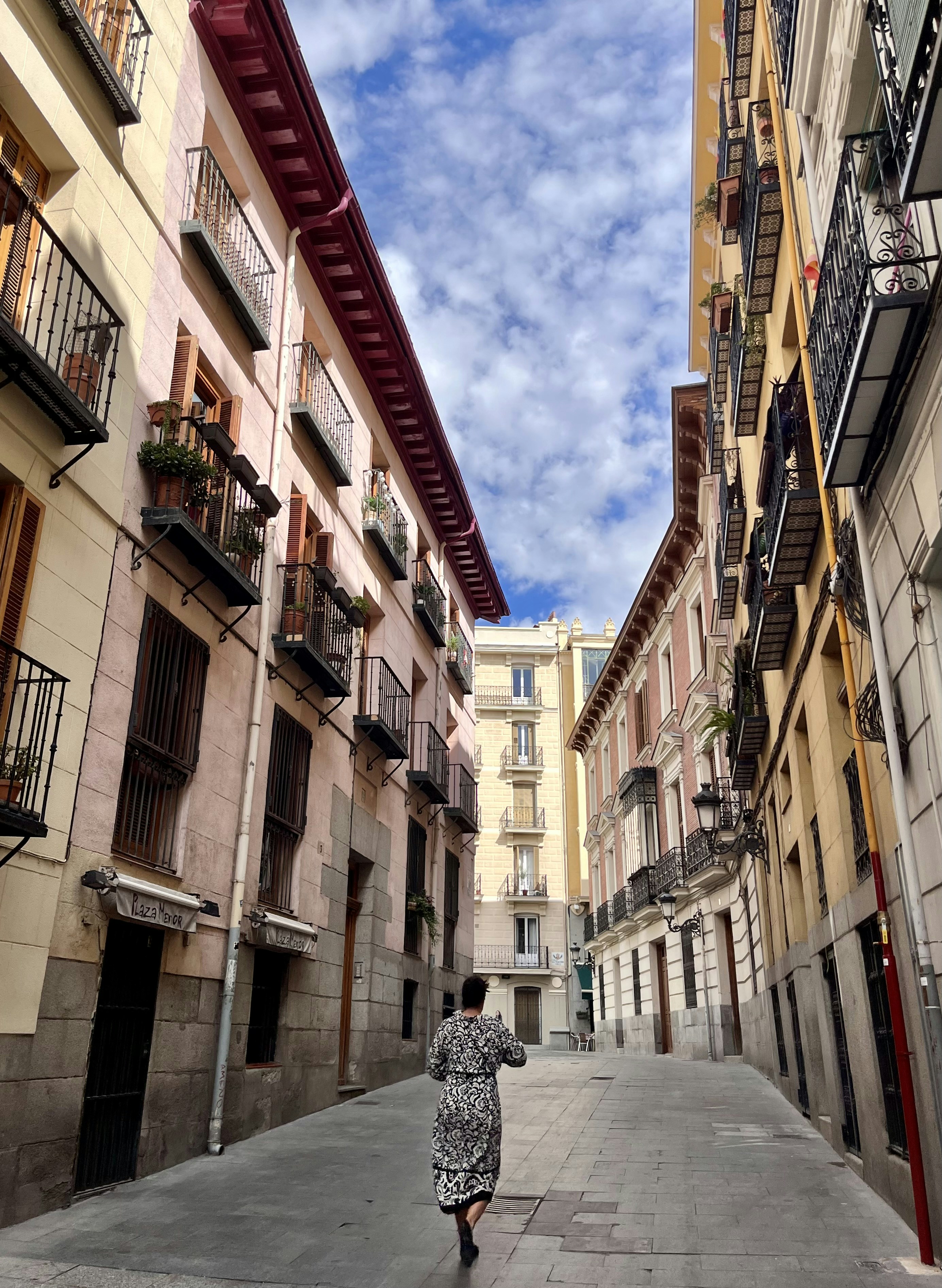 a woman walking down a street next to tall buildings
