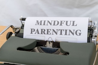 A vintage typewriter with a green body holds a sheet of paper displaying the words 'MINDFUL PARENTING' in bold, uppercase letters. The typewriter is placed on a light wooden surface, creating a classic and professional feel.