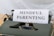 A vintage typewriter with a green body holds a sheet of paper displaying the words 'MINDFUL PARENTING' in bold, uppercase letters. The typewriter is placed on a light wooden surface, creating a classic and professional feel.