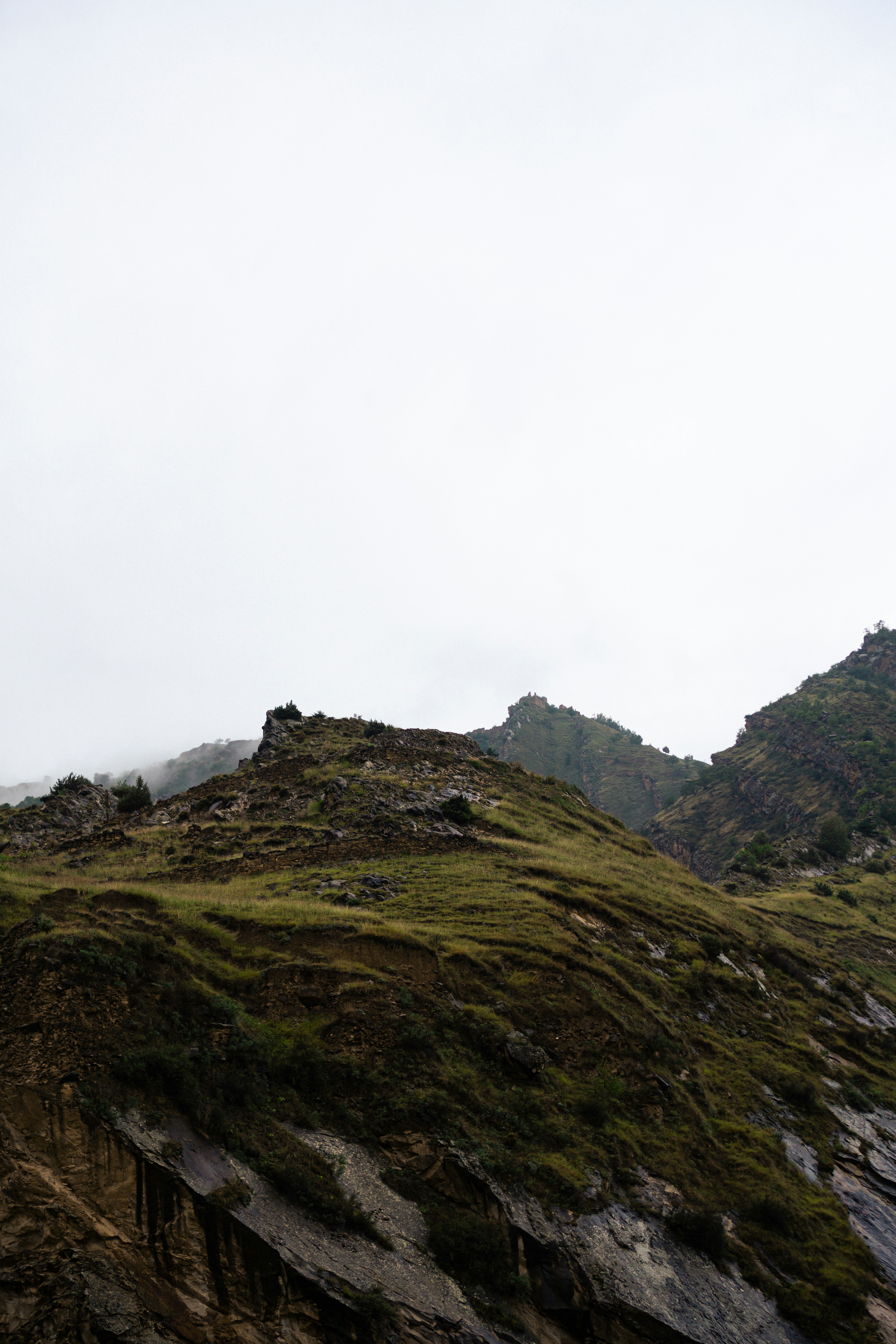 a hill covered in grass and rocks under a cloudy sky