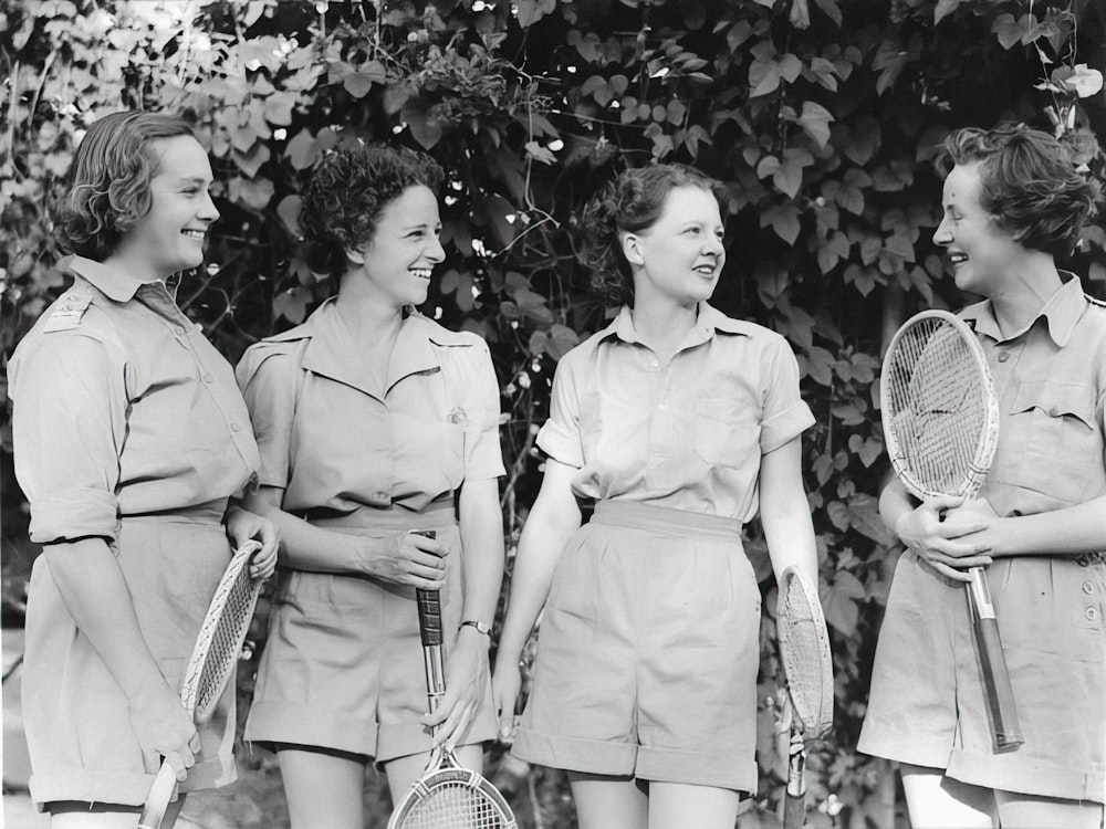 a group of women standing next to each other holding tennis racquets