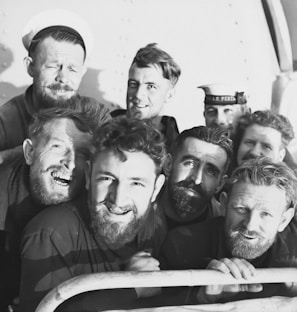 A group of elderly veterans in military uniforms smiling together.