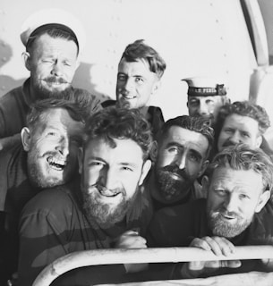 A group of elderly veterans in military uniforms smiling together.