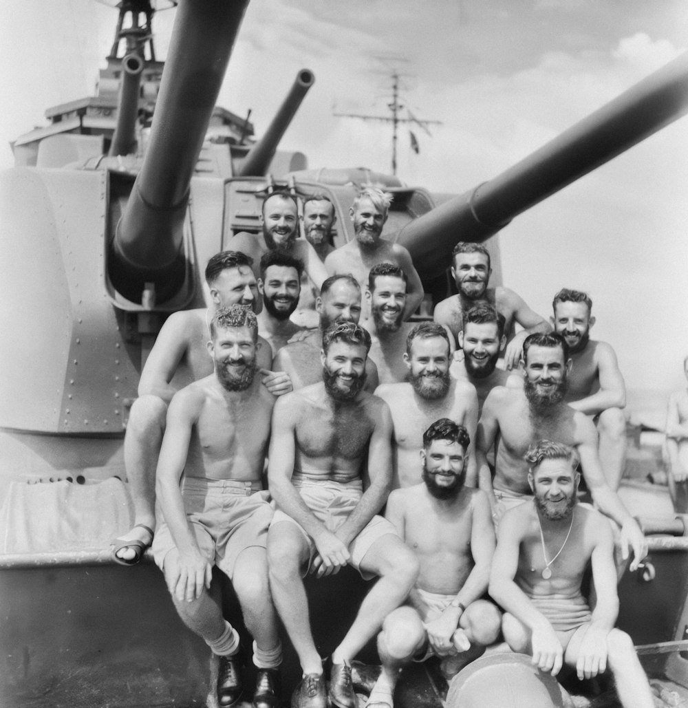 a group of men posing for a picture in front of a tank