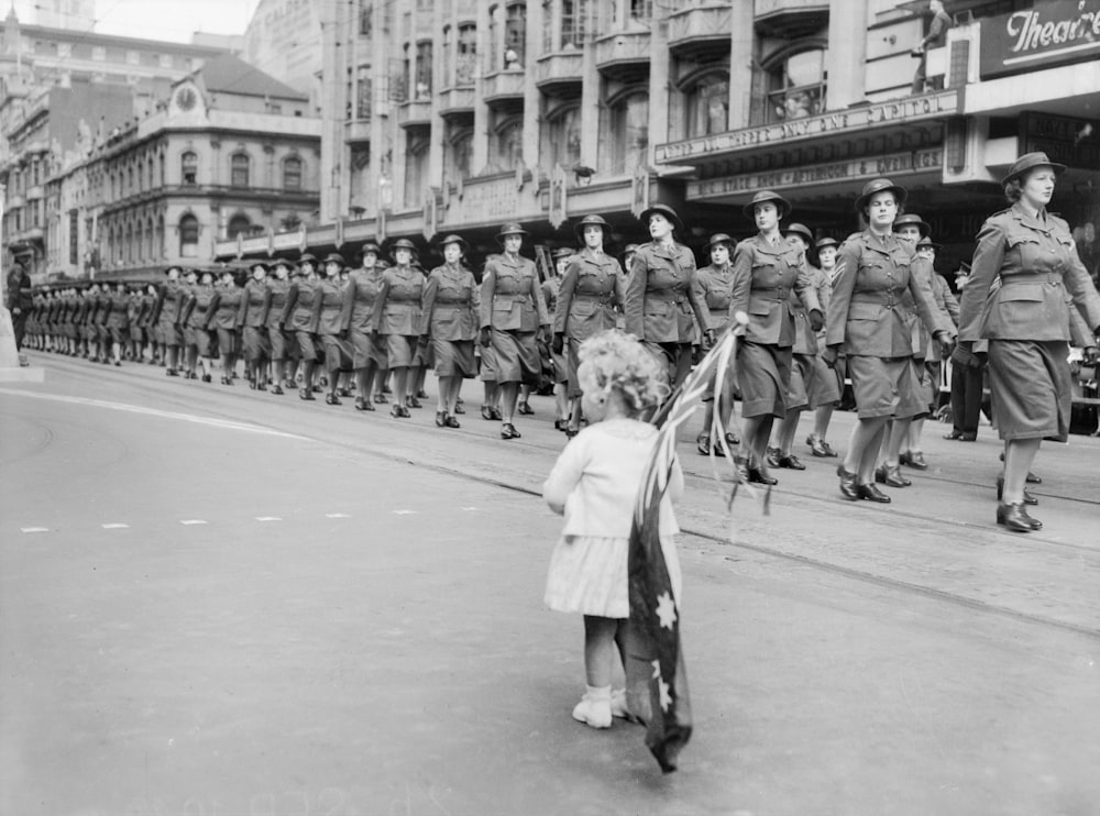 a little girl is standing in front of a line of soldiers