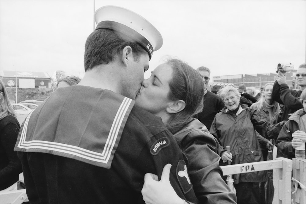 a sailor kissing a woman in front of a crowd of people
