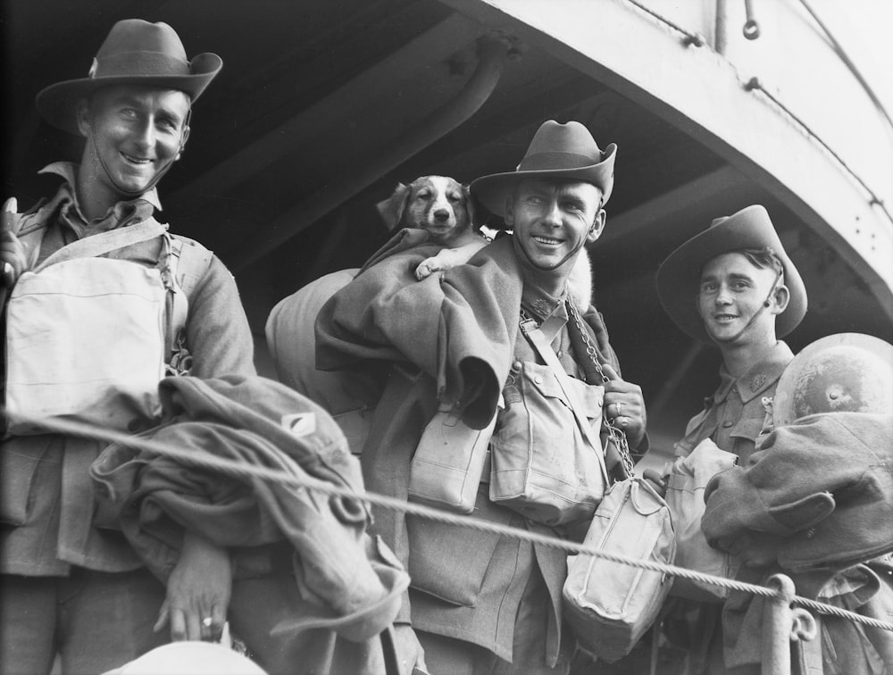 a black and white photo of three men and a dog