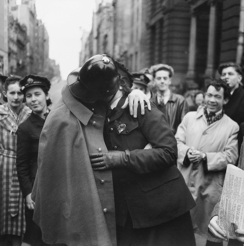 a man in a trench coat hugging a woman in a crowd of people