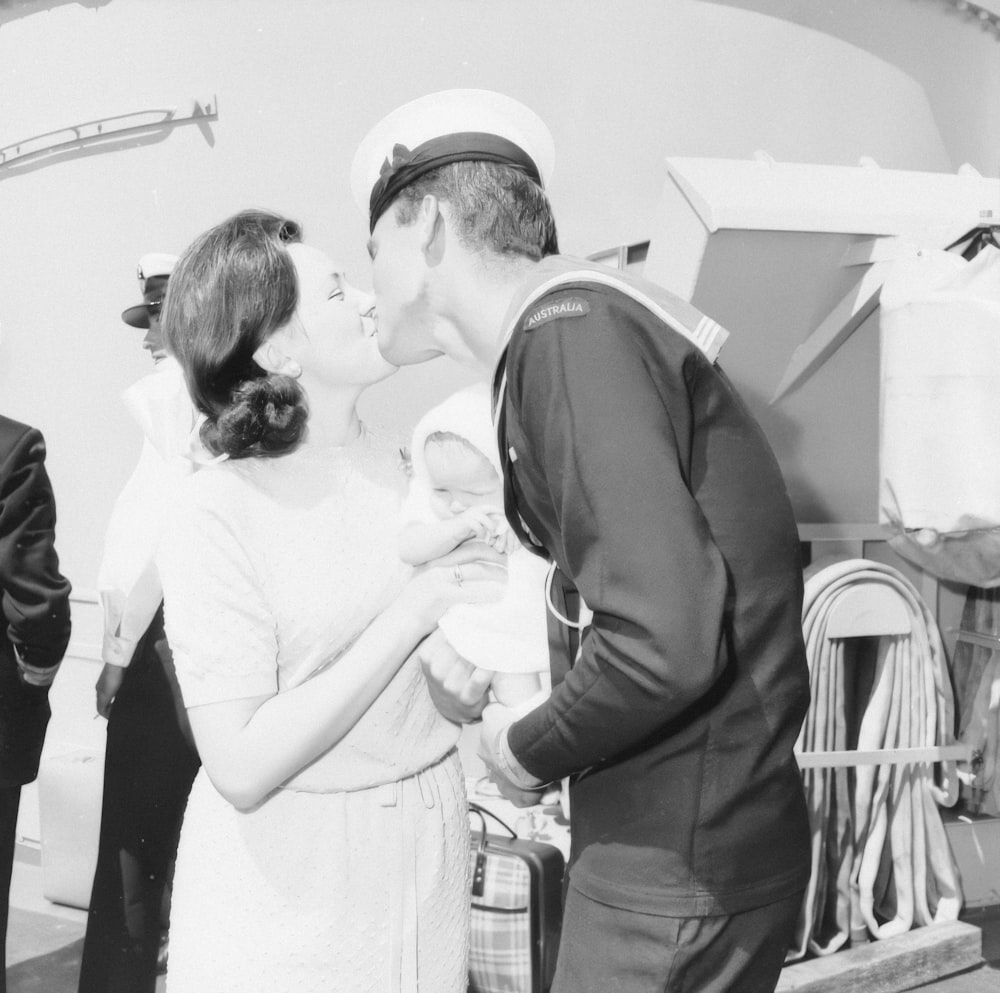 a black and white photo of a sailor kissing a woman