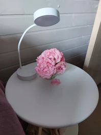 Close-up of a neatly arranged hotel room desk with a lamp and fresh flowers.