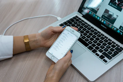 Close-up of hands typing on a laptop with a checklist on screen.