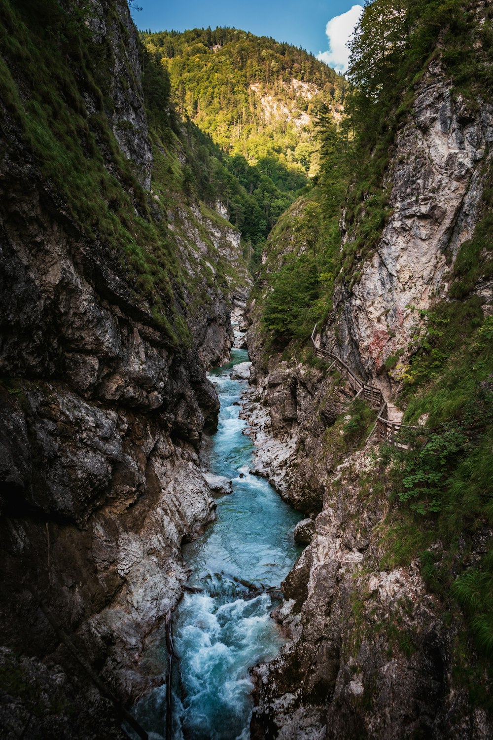 a river running through a canyon next to a lush green hillside