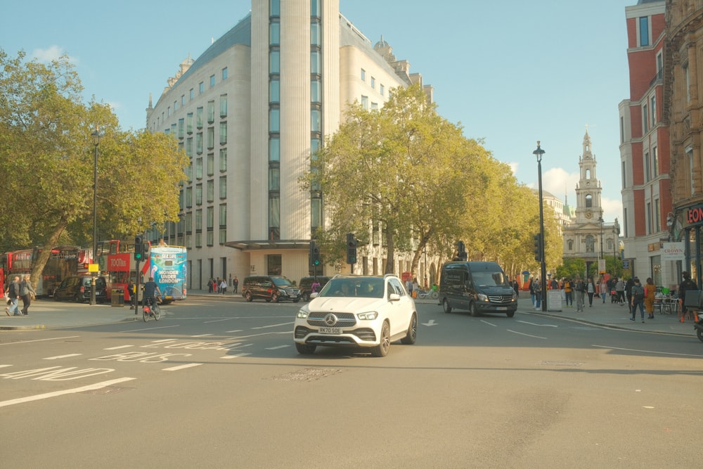 a white car driving down a street next to tall buildings