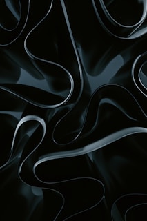 Abstract, flowing shapes with a glossy, dark appearance create a sense of depth and motion. The texture appears smooth and almost liquid-like.
