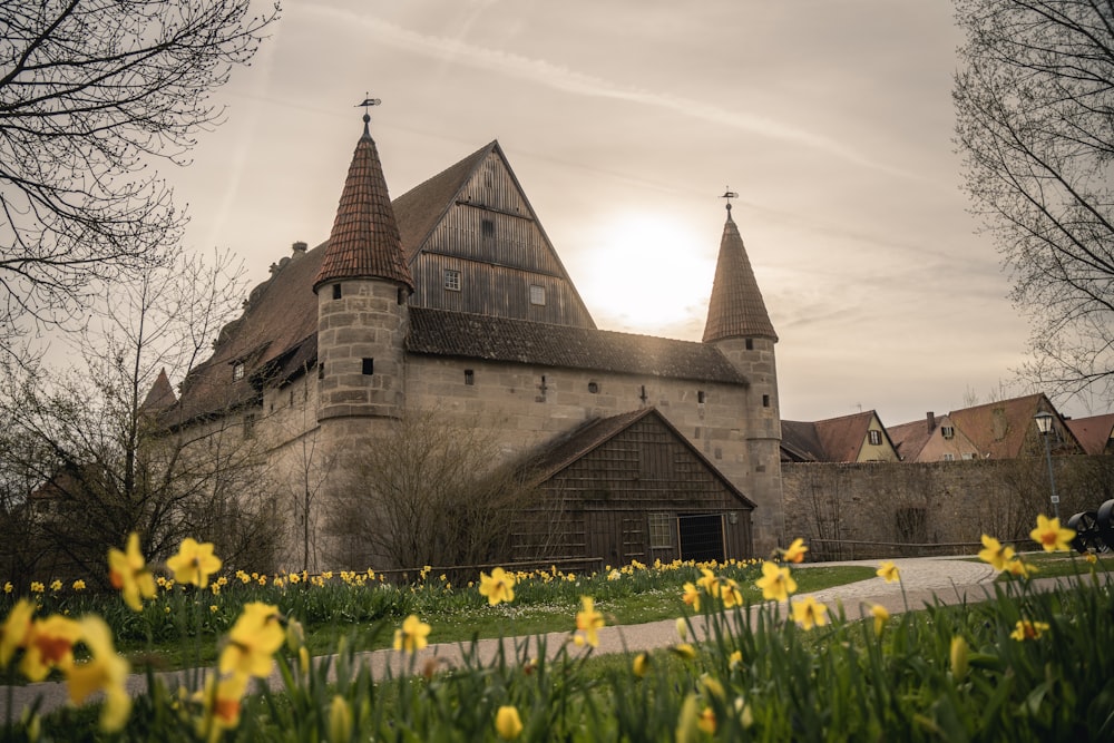 a large building with two towers and yellow flowers in front of it