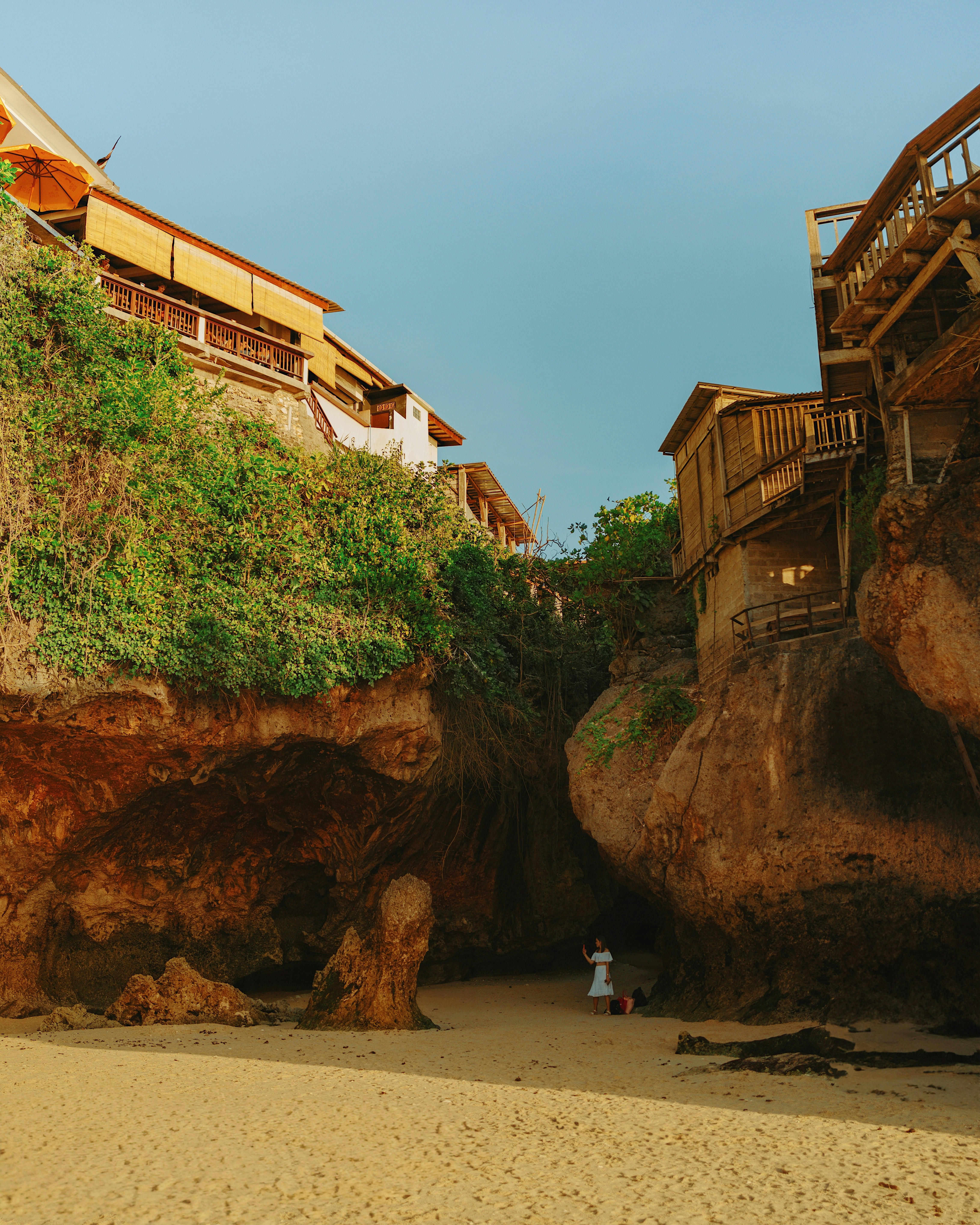 a person standing on a beach next to a cliff