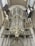 A large and ornate pipe organ is mounted within an interior space that features classical architecture. The organ is embellished with intricate designs and gilded accents. Surrounding the organ are decorative banners and columns, adding to the grandiose and historical ambiance.