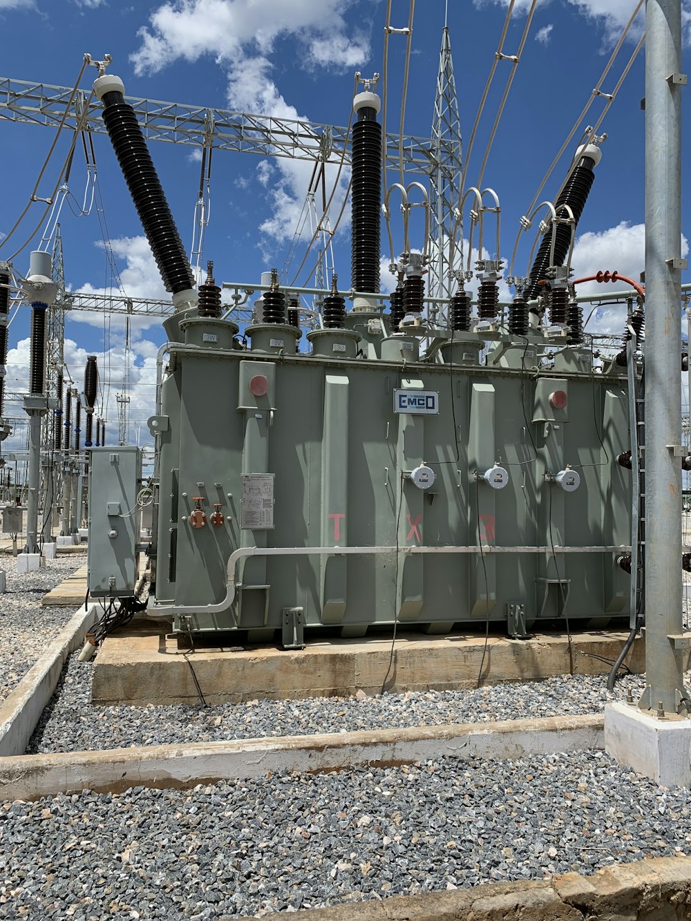 a row of electrical equipment sitting on top of a gravel covered ground