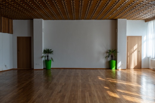 a large room with a wooden floor and two green vases