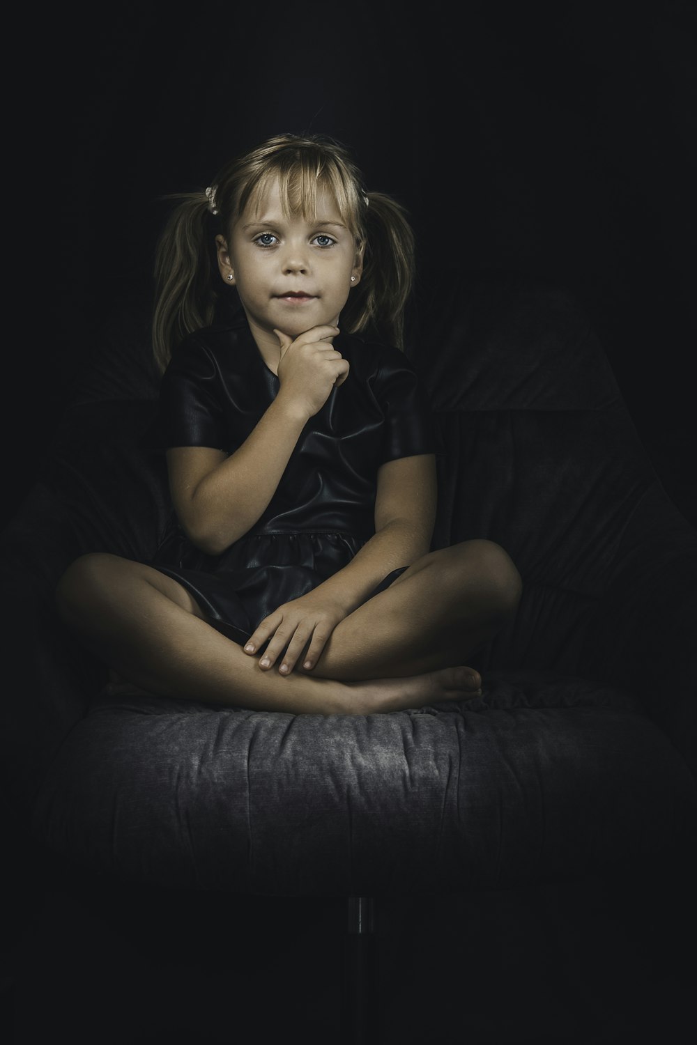 a little girl sitting on top of a black chair