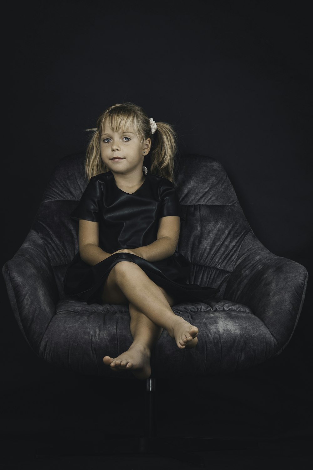 a little girl sitting on a black chair